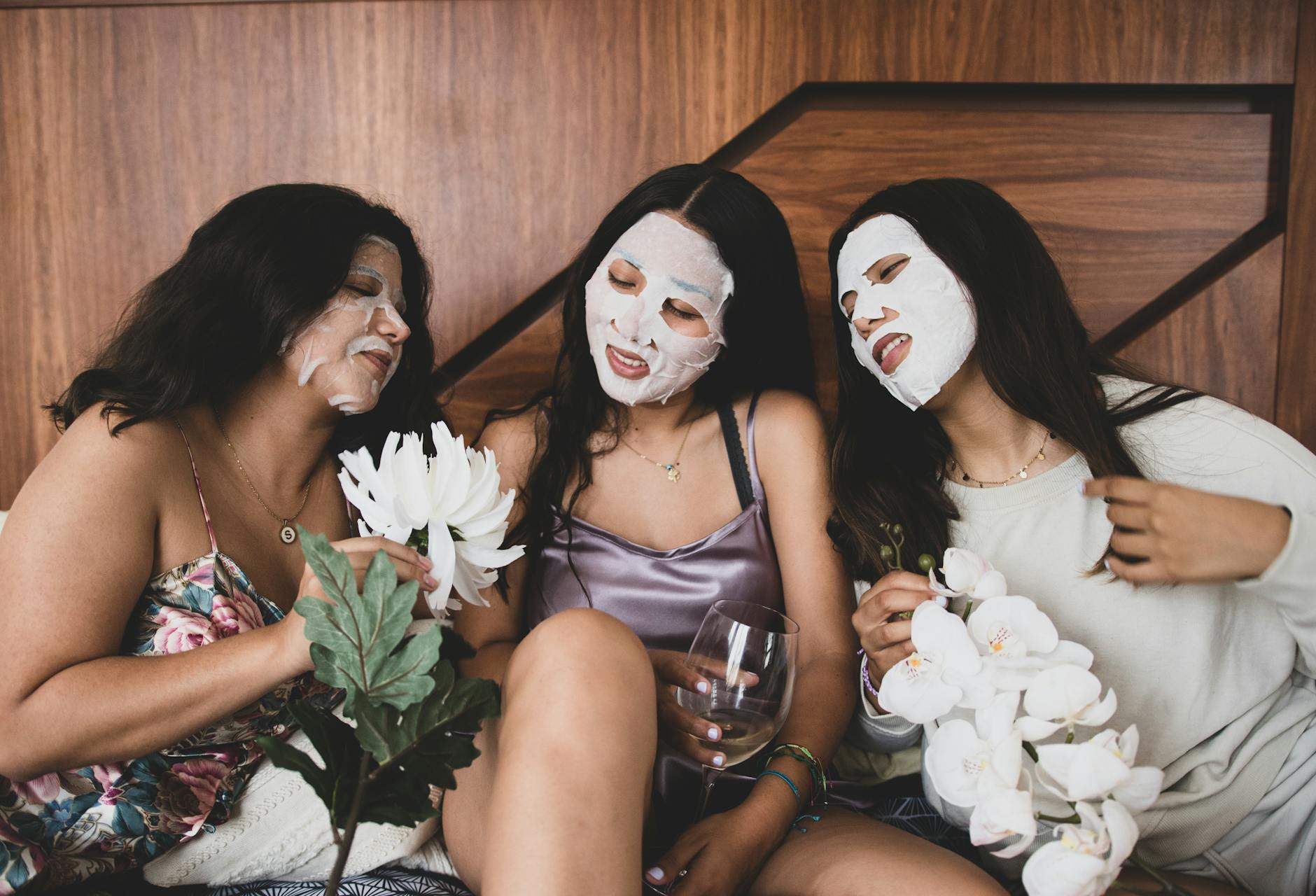 young women in beauty masks on faces relaxing together