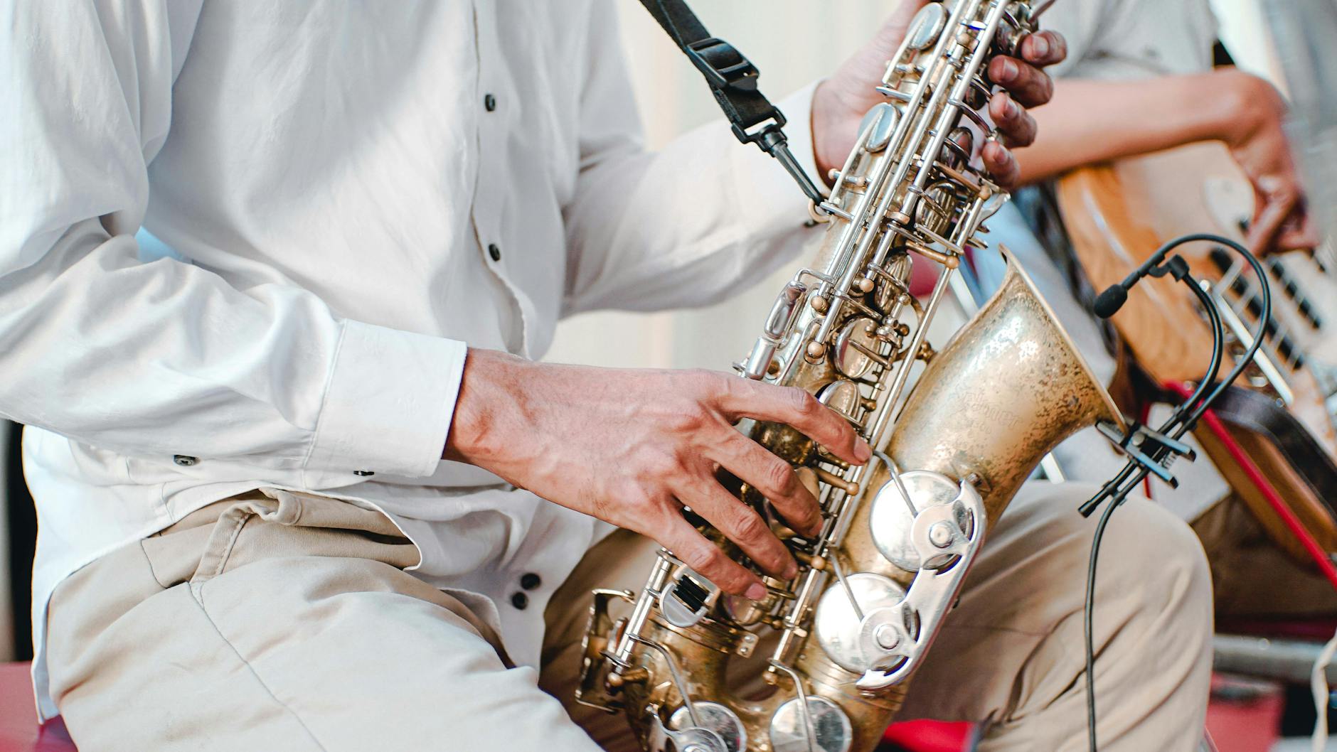 man in white shirt playing saxophone