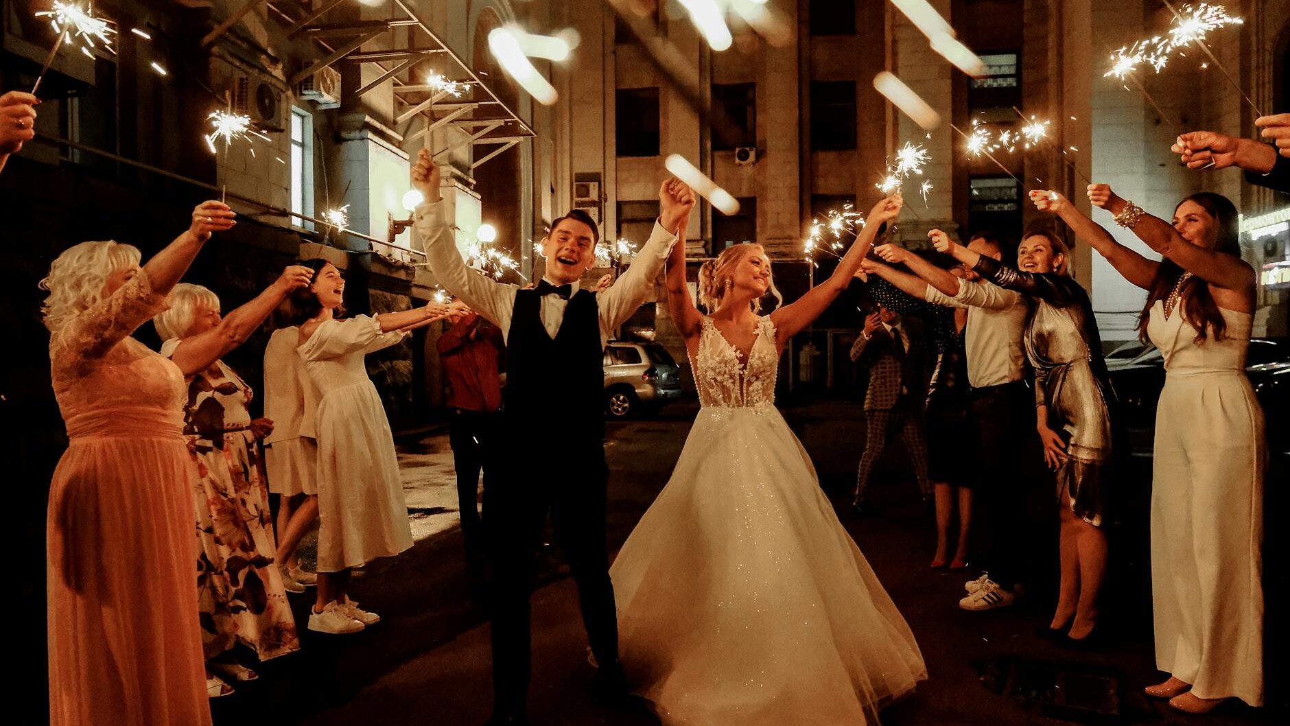 happy friends and newlywed couple celebrating wedding at night