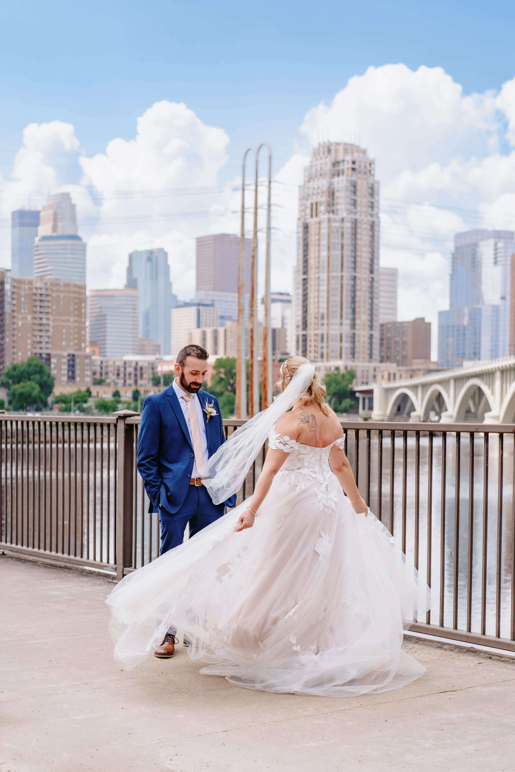 Bride and groom share a first look on Stone Arch Bridge with the Minneapolis skyline behind them