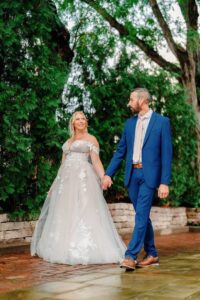 Bride and groom walking together in a garden setting, holding hands after their wedding ceremony.