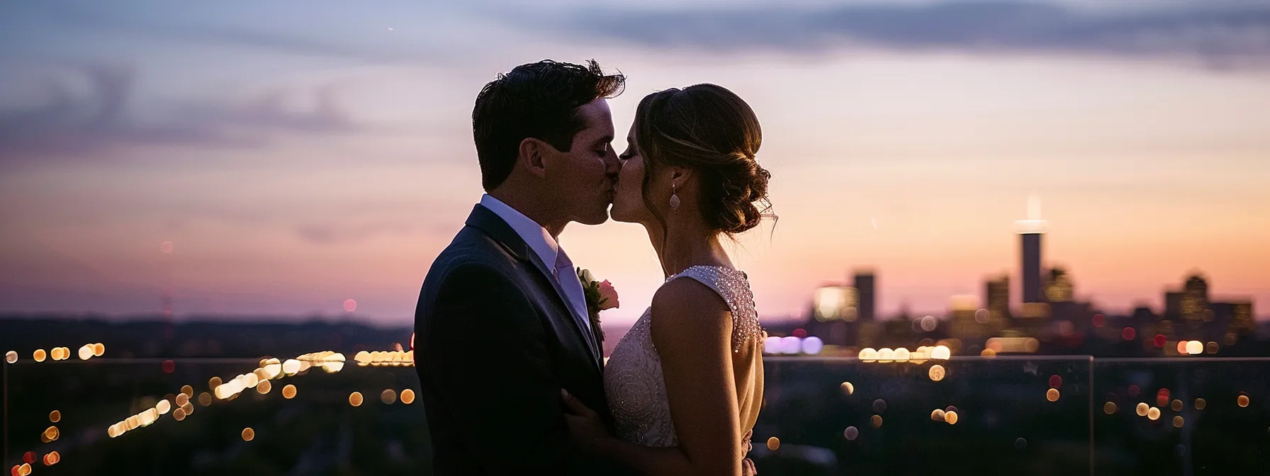 a newlywed couple sharing a kiss on a rooftop overlooking the sparkling minneapolis city skyline. rooftop wedding venues in minneapolis