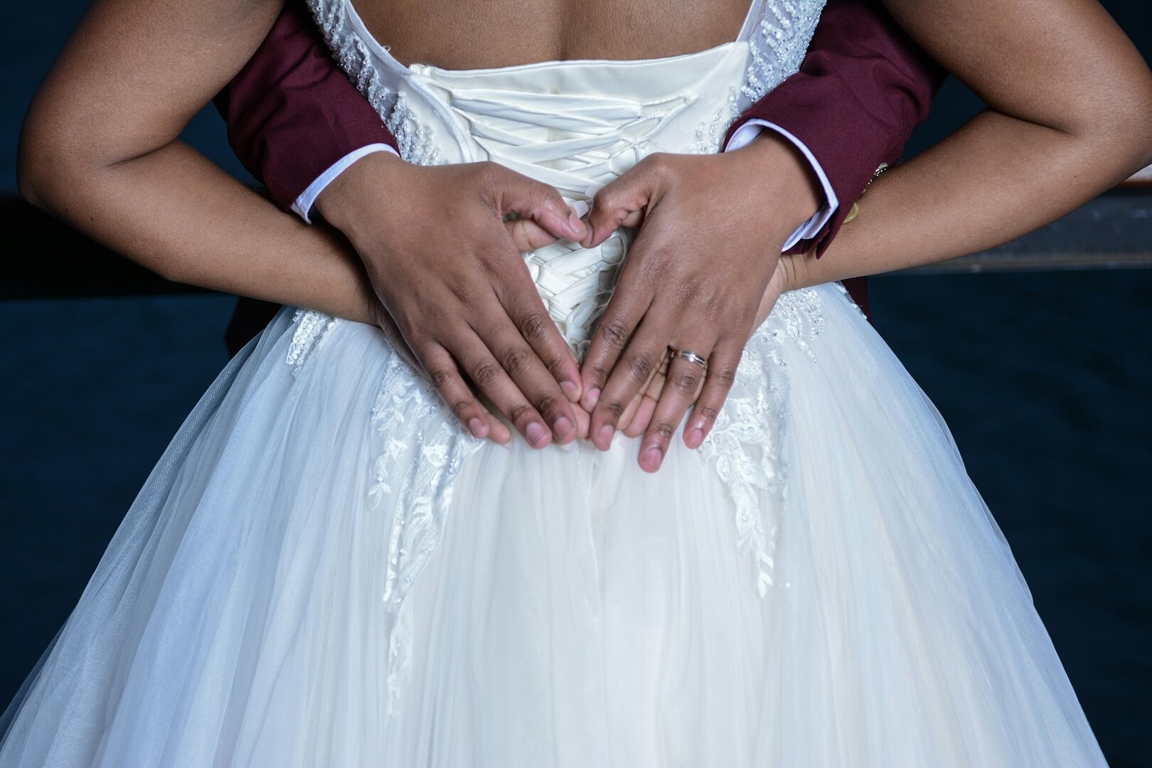 bride and groom posing, with groom's hands over brides. he hugs from behind