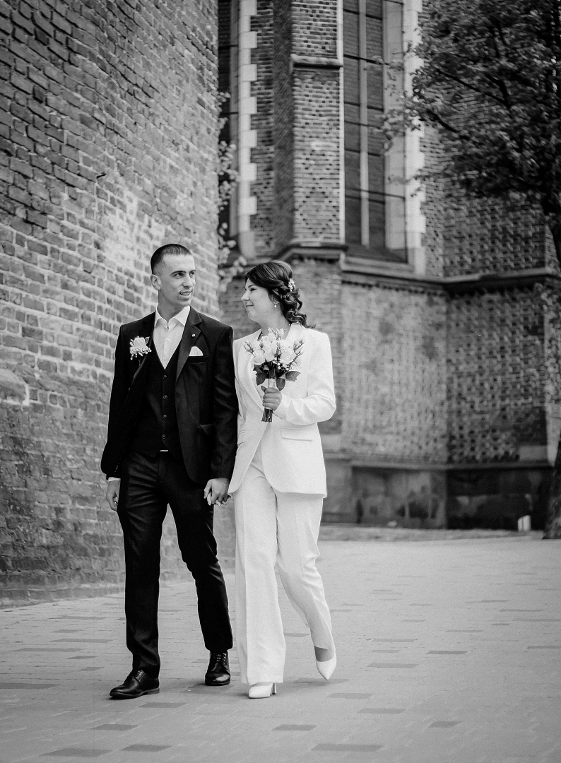 bride and groom walking in front of brick building