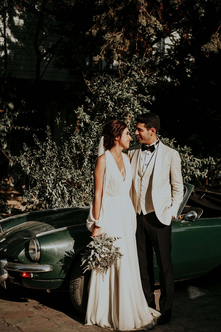 bride and groom in front of car, smiling intimately